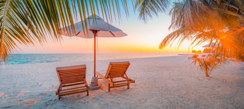 Tranquil tropical sunset scenery couple sun bed loungers, umbrella palm tree leaves. White sand sea view horizon, colorful twilight sky, calmness relaxation. Luxury vacation travel beach resort hotel © icemanphotos