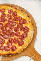 Pepperoni Pizza Homemade Artesanale Close Up Detail on a Round Wooden Plate with Flour Background Table