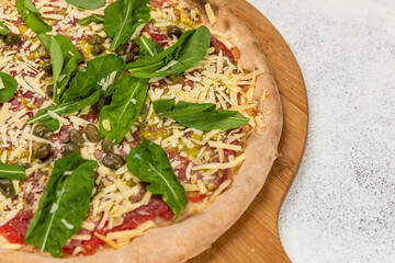 Pizza Carpaccio Homemade Artesanale Close Up Detail on a Round Wooden Plate with Flour Background Table