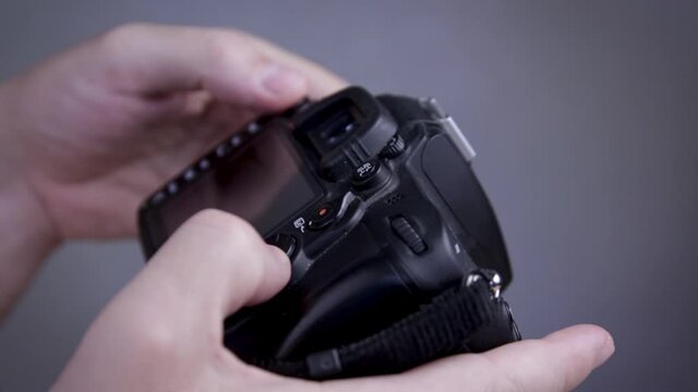 A photographer adjusts the camera. The fingers of the photographer are pushing the camera