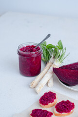 A jar of homemade beet-horseradish hummus. with a spoon in the middle. Organic food isolated on a white background. 