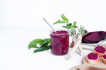 A jar of homemade beet-horseradish hummus. with a spoon in the middle. Organic food isolated on a white background. High quality photo