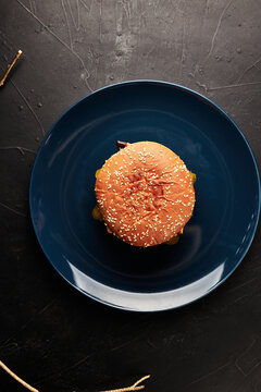 burger on a blue plate on a black background with a golden twig overhead view