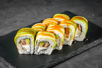 appetizing green dragon sushi roll with philadelphia cucumber eel and avocado cheese on a black...