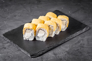 appetizing cheese sushi roll with philadelphia and tofu cheese on a black stone plate