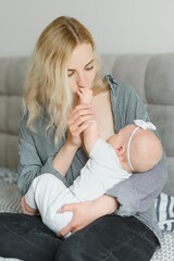 Breastfeeding Concept. Beautiful young woman lactating her toddler baby on couch at home, copy space