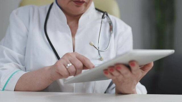 Female Doctor Using Tablet At Medical Workplace. Close Up Of Medical Specialist Touch Tablet Screen. Nurse Using Tablet Pc. Woman Doctor Working With Ipad. Modern Technology For Medical Workers.