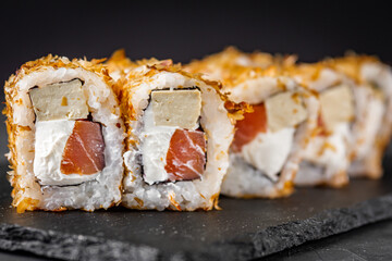 appetizing sushi roll with tuna cheese and tofu on a black stone plate
