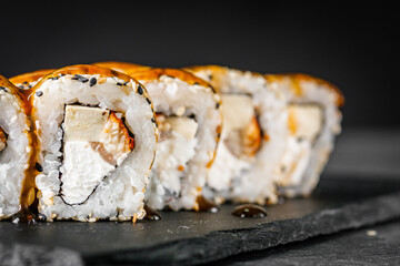 appetizing sushi roll california with eel tofu sesame and unagi cheese on a black stone plate