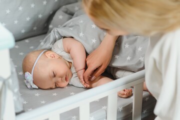 Young mother with their newborn baby near bed cot