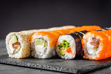 appetizing set of sushi roll on a black stone plate