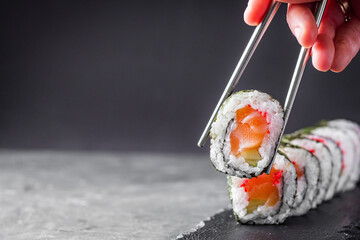 appetizing sushi roll maki with salmon on a black stone plate © Narsil