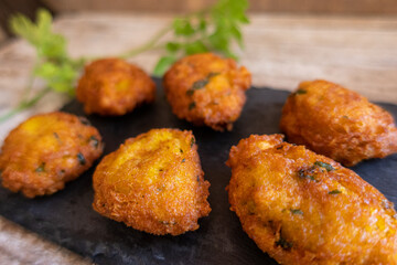 salty fritters with parsley, served on a slate plate and a rustic wood background.