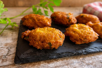 salty fritters with parsley, served on a slate plate and a rustic wood background.