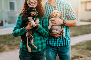 Young couple adopting beautiful dogs at animal shelter..