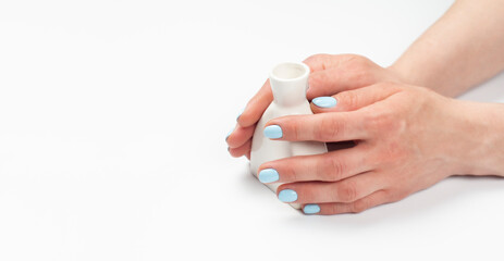 A vase in the hands of a woman with a turquoise manicure. Hands with manicure. On white background. Beautiful skin.