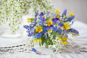 Keuken spatwand met foto A bouquet of spring blue, yellow flowers in a vase on the table. Pansies, forget-me-nots, primroses, bird cherry, violets, muscari. Postcard, blur, selective focus. © tachinskamarina