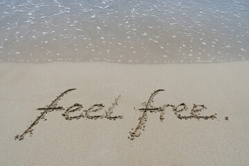 feel free handwriting in sand on the beach inspirational background