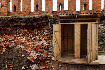 an old dirty wooden toilet among the ruins. a latrine in a poor neighborhood among garbage and...