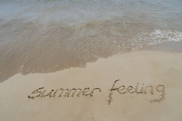 summer feeling handwriting in fine sand on the beach motivational background