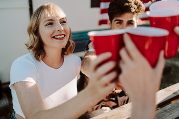 Amigos brindando con vasos rojos en una barbacoa por el 4 de julio día de la independencia de estados unidos