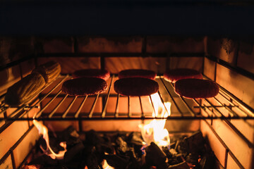 Silueta de hamburguesas cocinándose en una barbacoa con el fuego candente