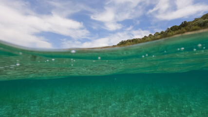 Split underwater photo of exotic Caribbean island seascape with emerald sea and beautiful clouds