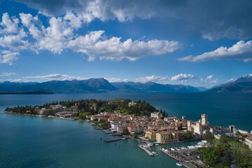 Fototapeta na wymiar Sirmione, Lake Garda, Italy. Panorama of Lake Garda. Castle on the water in Italy. Peninsula on a mountain lake in the background of the alps. Aerial view of the island of Sirmione.