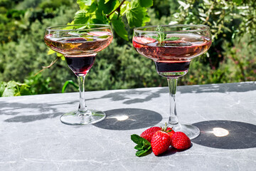 Fresh summer strawberry cocktail or mocktail on the table in garden.Creative drink beverage on sunlight with shadows