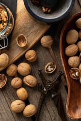 Tasty walnuts with cracked split nutshells, jaw and dragon nutcracker on rustic napkin and wood table. vertical