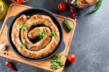 Grilled spiral sausage with spices in a frying pan on a stone background. Top view from above and copy space