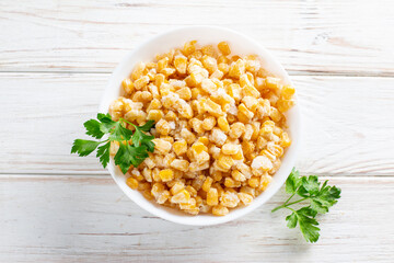 Frozen corn in a plate on white table. Frozen food. Top view. Copy space