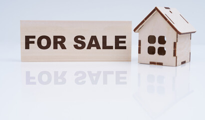 There is a wooden house and a sign on the table - For sale