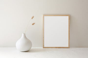 11x14 minimalist, thin wood frame mockup. Modern white vase with dried grass decor on a white textured table. 