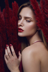 Young beautiful woman with red lips. Woman in red fluffy clothes. Decorative cosmetics and make-up.