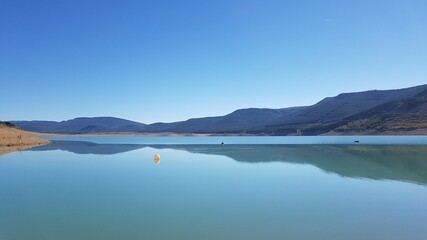 Fototapeta na wymiar un bonito y tranquilo lago de montañas con agua azul limpia y cielo azul en España