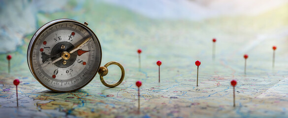 Magnetic compass  and location marking with a pin on routes on world map. Adventure, discovery,...