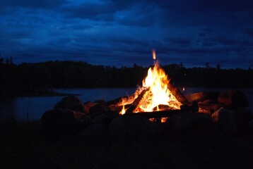 camp fire burning in a fire pit next to the lake