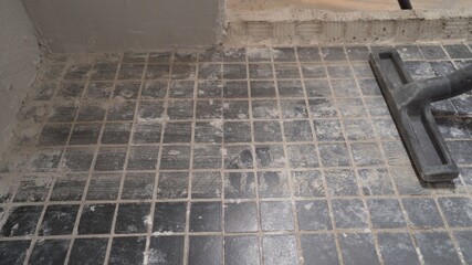 A worker is cleaning dust with a vacuum cleaner on the floor. Cleaning service. dust removal with vacuum cleaner. Worker removes dust with a vacuum cleaner. Worker vacuuming the floor before