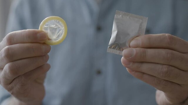 Male hands taking condom out of package, aids awareness and sti prevention