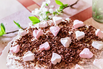 Festive cake with cream and chocolate, decorated with hearts.