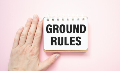 Closeup on businessman holding a card with text GROUND RULES, business concept image with soft focus background and vintage tone