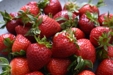 Beautiful fresh strawberries in a plate on a concrete background.