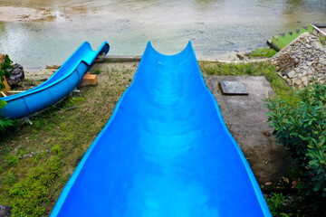 First person view of a blue waterslide, looking down the waterslide into the water