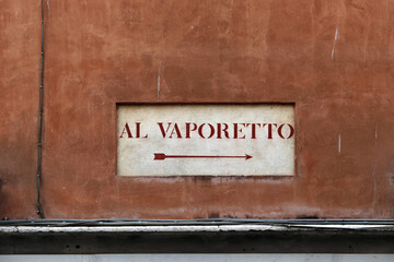 Old road sign "Al Vaporetto" on a wall in Venice with a arrow to indicate the direction to the boat pier for water bus.