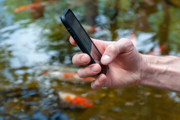 Man holding smartphone, closeup of hand. Process of taking a photo using smartphone. Hand Use Modern cell phone. Hand taking a picture with smartphone