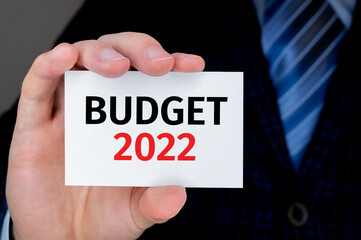 BUDGET 2022 written on a bussiness card held by a businessman.