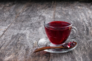 Red hibiscus tea in glass cup on wooden table