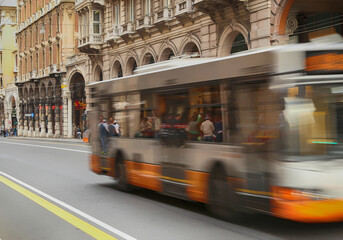 Motion blurred of orange urban bus traveling on a main road in a urban contest with historical houses and arcade in background. XX Settembre Street in the Genoa downtown, Italy. © M.Scarselletta
