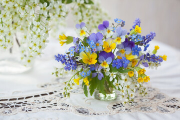A bouquet of spring blue, yellow flowers in a vase on the table. Pansies, forget-me-nots,...